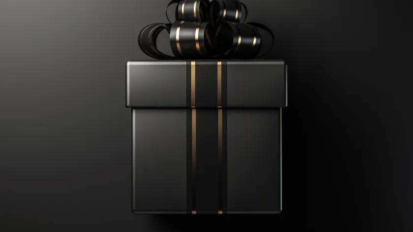 Elegant black gift box with glossy gold striped ribbon and decorative bow on a dark background.